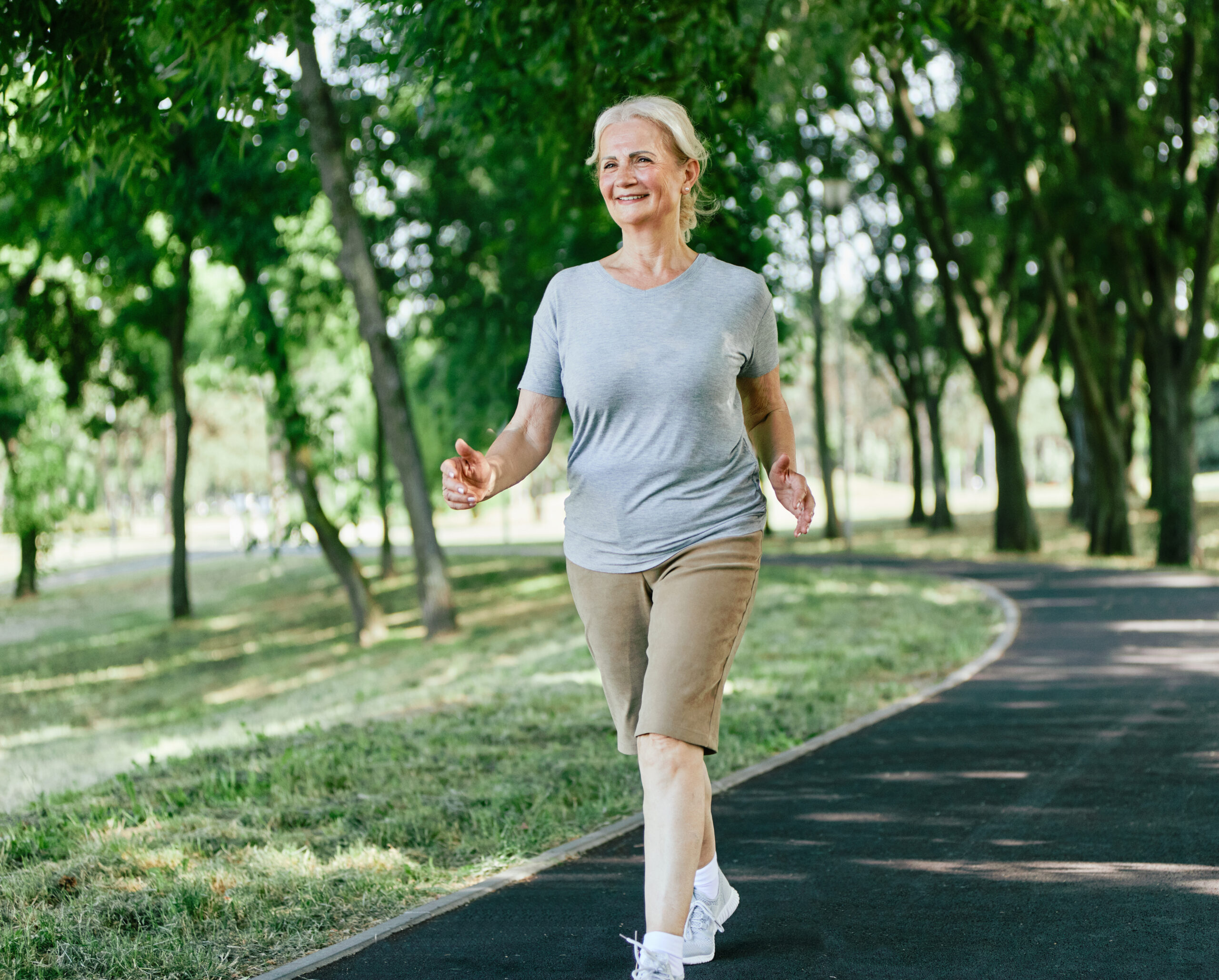 Femme senior active en extérieur, marche dynamique dans un parc